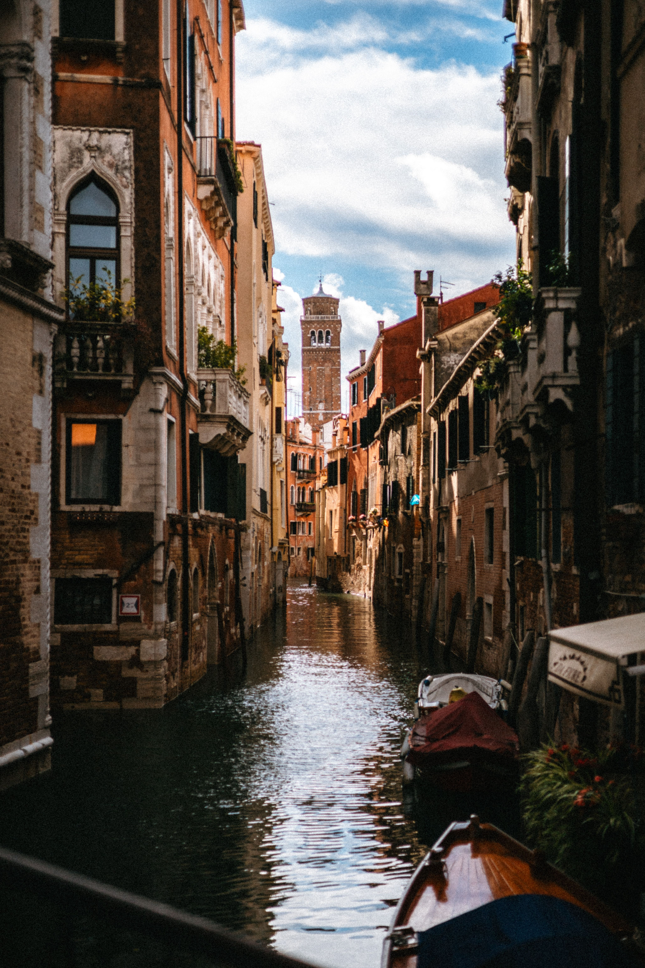 Rio veneziano incorniciato da case colorate, con campanile in fondo sotto un cielo nuvoloso